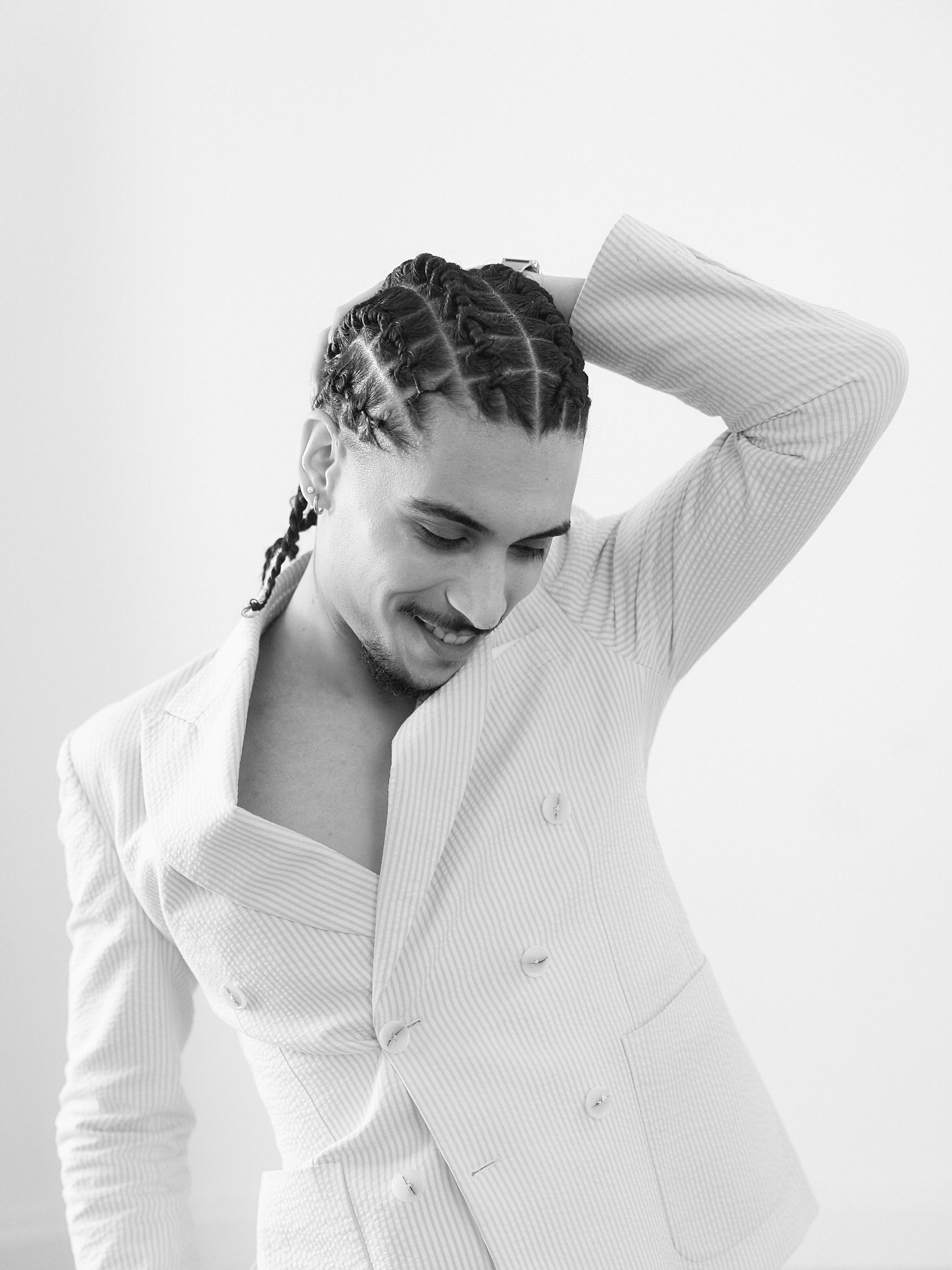 Portrait d'un homme élégant en costume rayé, coiffure tressée, capturé par un photographe de mariage dans le Var. Photographie en noir et blanc.